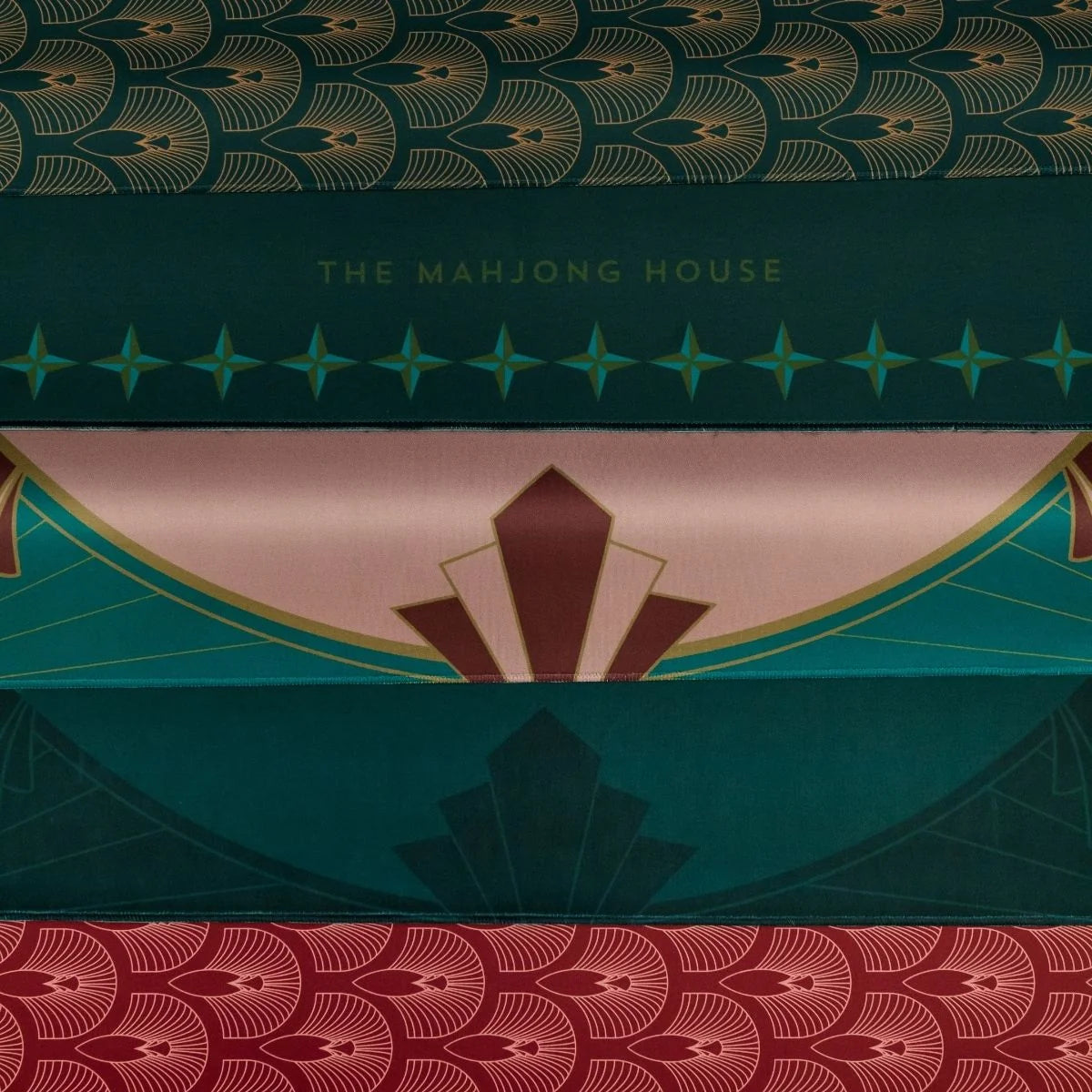 Close-up of Deco Circle mat patterns in pink and teal alongside coordinating fan-patterned designs and The Mahjong House branding